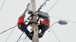 A crew installs a concentrator on a concrete pole A crew installs a concentrator on a concrete pole