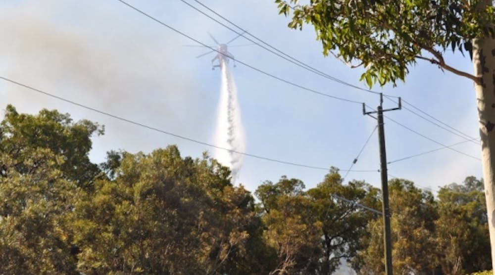 A chopper dumps water on the Jolimont blaze, with emergency appliances and firefighters in the foreground. Picture: Dom White