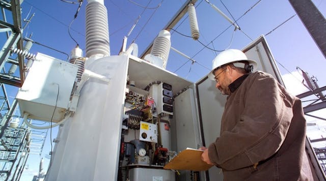 An Idaho National Laboratory power engineer examines breaker settings inside the yard of an electric substation.