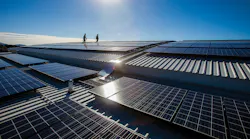 Two persons walk past an array of PV panels