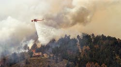 June 11, 2012, a Sikorsky S-64 Aircrane firefighting helicopter drops water on a hot spot burning close to homes near Horsetooth Reservoir near Laporte, Colorado. Photo by Marc Piscotty/Getty Images.