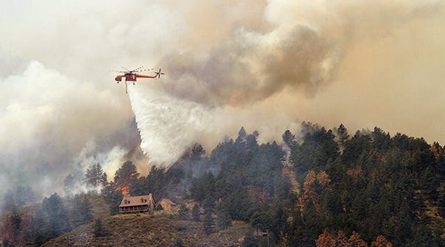 June 11, 2012, a Sikorsky S-64 Aircrane firefighting helicopter drops water on a hot spot burning close to homes near Horsetooth Reservoir near Laporte, Colorado. Photo by Marc Piscotty/Getty Images.