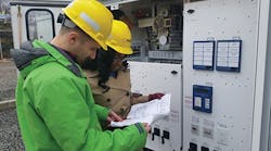 PSE&amp;G engineers review a wiring diagram in preparation of testing the alarm inputs on the SEL 2414 transformer monitoring equipment.