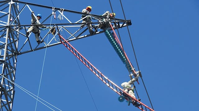 Wearing conductive suits, Manitoba Hydro live-line crew bonds to the conductor to perform energized work, using the barehand ladder method at 500-kV HVDC.