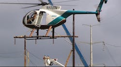 Helicopters offer air support for linemen working from a bucket truck Helicopters offer air support for linemen working from a bucket truck