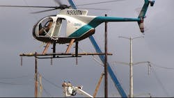 Helicopters offer air support for linemen working from a bucket truck Helicopters offer air support for linemen working from a bucket truck