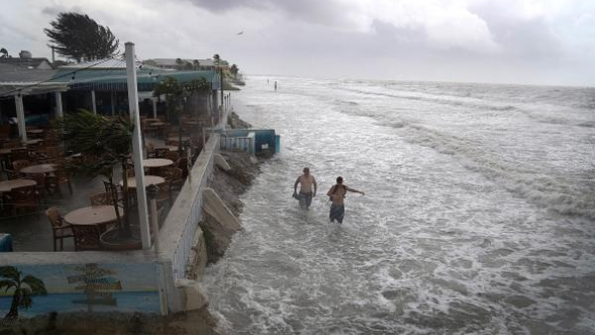 People walk along the beach as waves from Tropical Storm Colin crash along the shore on Fort Myers Beach on June 6 2016 in Fort Myers Florida The Florida Gov Rick Scott declared a state of emergency with Tropical Storm Colin that brings a serious threat of flooding
