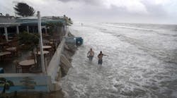 People walk along the beach as waves from Tropical Storm Colin crash along the shore on Fort Myers Beach on June 6, 2016 in Fort Myers, Florida. The Florida Gov. Rick Scott declared a state of emergency with Tropical Storm Colin that brings a serious threat of flooding.