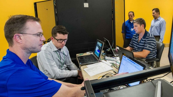 From left to right NREL39s Brian Miller works with David Cronin of DC Systems Duane Petersen then with Scitor Corporation Brandon Hjella of FireEye and NRELrsquos Erfan Ibrahim to build the Test Bed for Secure Distributed Grid Management a hardware system that mimics the communications power systems and cybersecurity layers for a utility39s power distribution system