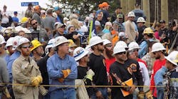 Linemen gather near the sidelines to watch their coworkers compete at the 2016 International Lineman&rsquo;s Rodeo in Bonner Springs, Kansas.