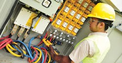 A technician measures low-voltage load on a medium-voltage/low-voltage distribution transformer.