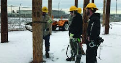 Instructor Colin Davies of the IBEW-NECA shows students in the Electrical Lineworker Certificate Program how to climb a utility pole at Eversource&rsquo;s training yard in Hooksett.