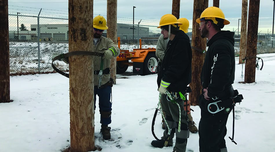 Instructor Colin Davies of the IBEW-NECA shows students in the Electrical Lineworker Certificate Program how to climb a utility pole at Eversource&rsquo;s training yard in Hooksett.