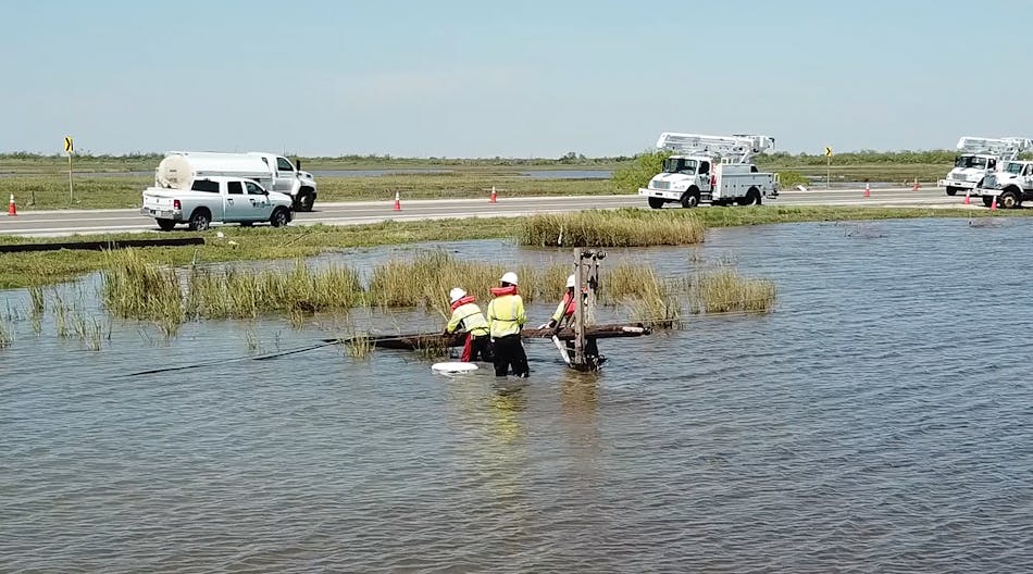 Linemen from Irby Construction stand in knee-deep water to help restore power on the southeast Texas coast.