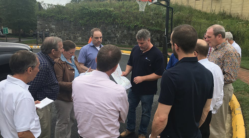 During a bus tour of the Idylwood-Tysons project study area, a Dominion Energy representative talks with advisory group participants in a neighborhood about underground construction techniques along a potential route, as well as the proximity to an existing transmission structure and sound wall.