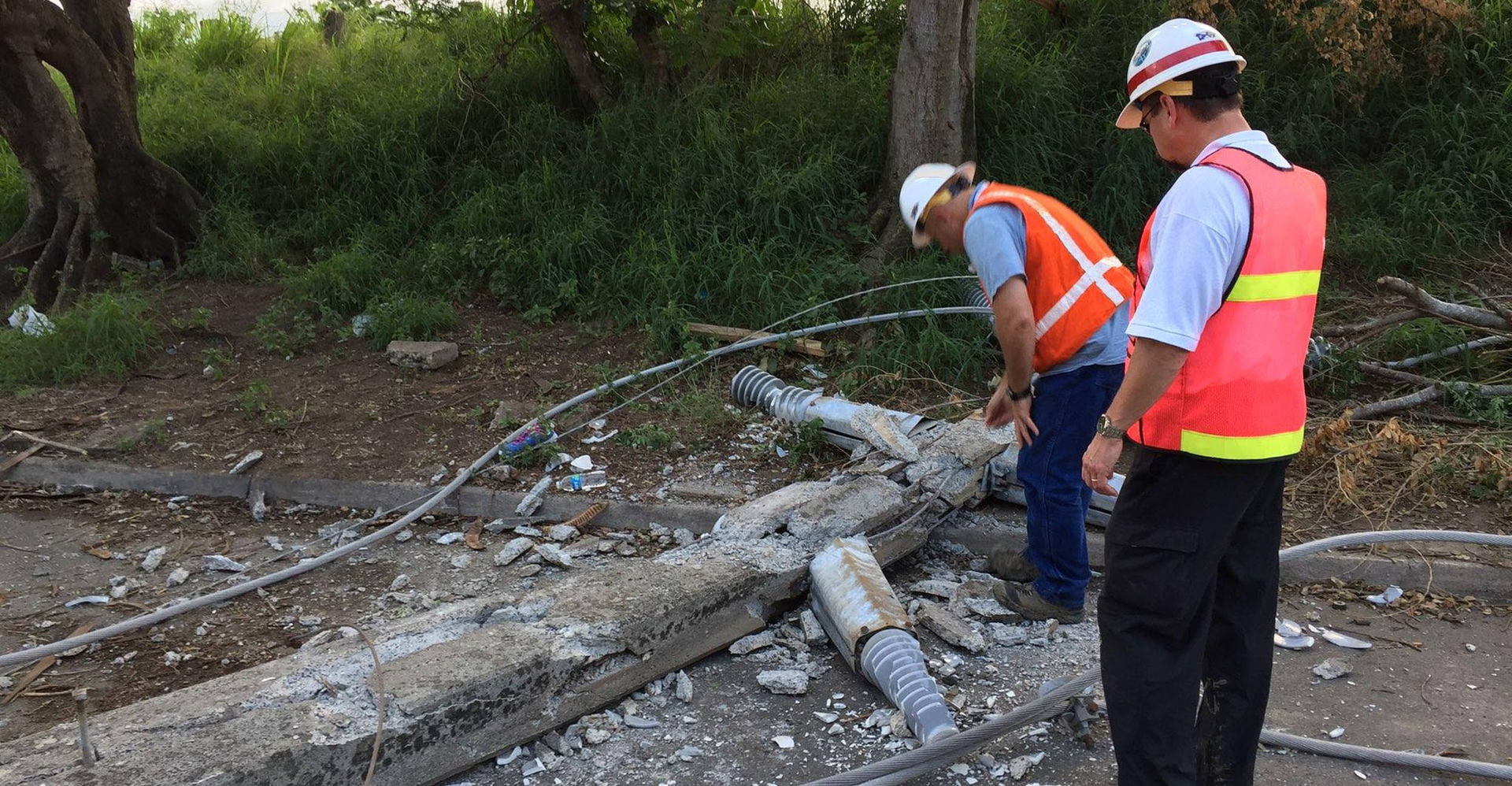 concrete pole on ground with linemen inspecting it