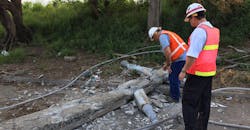 concrete pole on ground with linemen inspecting it concrete pole on ground with linemen inspecting it