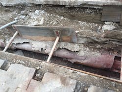 A steam line exposed, resulting in no insulation and the deteriorated outer pipe.