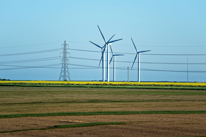 Meadow with Wind mill turbines generating electricity and electric power lines, in England, the UK