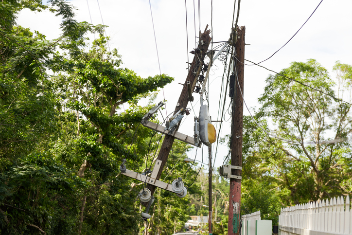 Hurricane Maria aftermath in Puerto Rico. Dangerous power lines and power pole dangle over street traffic in Vega Alta, Puerto Rico