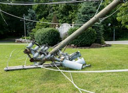 Broken snapped wooden power line post with electrical components on the ground after a storm Broken snapped wooden power line post with electrical components on the ground after a storm