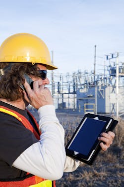 Power line technician using smart phone and digital tablet at a worksite. Power line technician using smart phone and digital tablet at a worksite.
