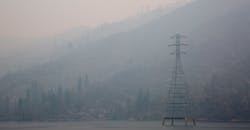 A transmission line stands on the water in the smoke.