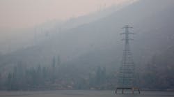 A transmission line stands on the water in the smoke.