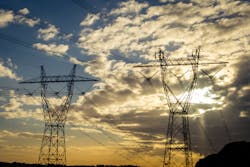 Electricity distribution network metaphor. Sunset silhouette of two high voltage power pylons and power lines. National Grid, sunflare, horizontal, Electricity distribution network metaphor. Sunset silhouette of two high voltage power pylons and power lines. National Grid, sunflare, horizontal,