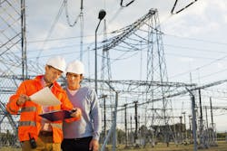 Male architects reviewing documents together at electric power plant Male architects reviewing documents together at electric power plant