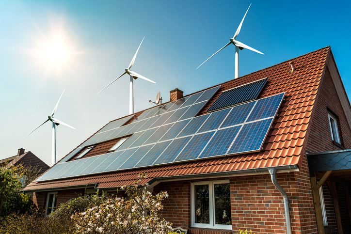 Solar panel on a roof with wind turbines in the background