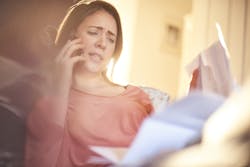 A sitting woman looking at a sheaf of papers and talking on a mobile phone A sitting woman looking at a sheaf of papers and talking on a mobile phone
