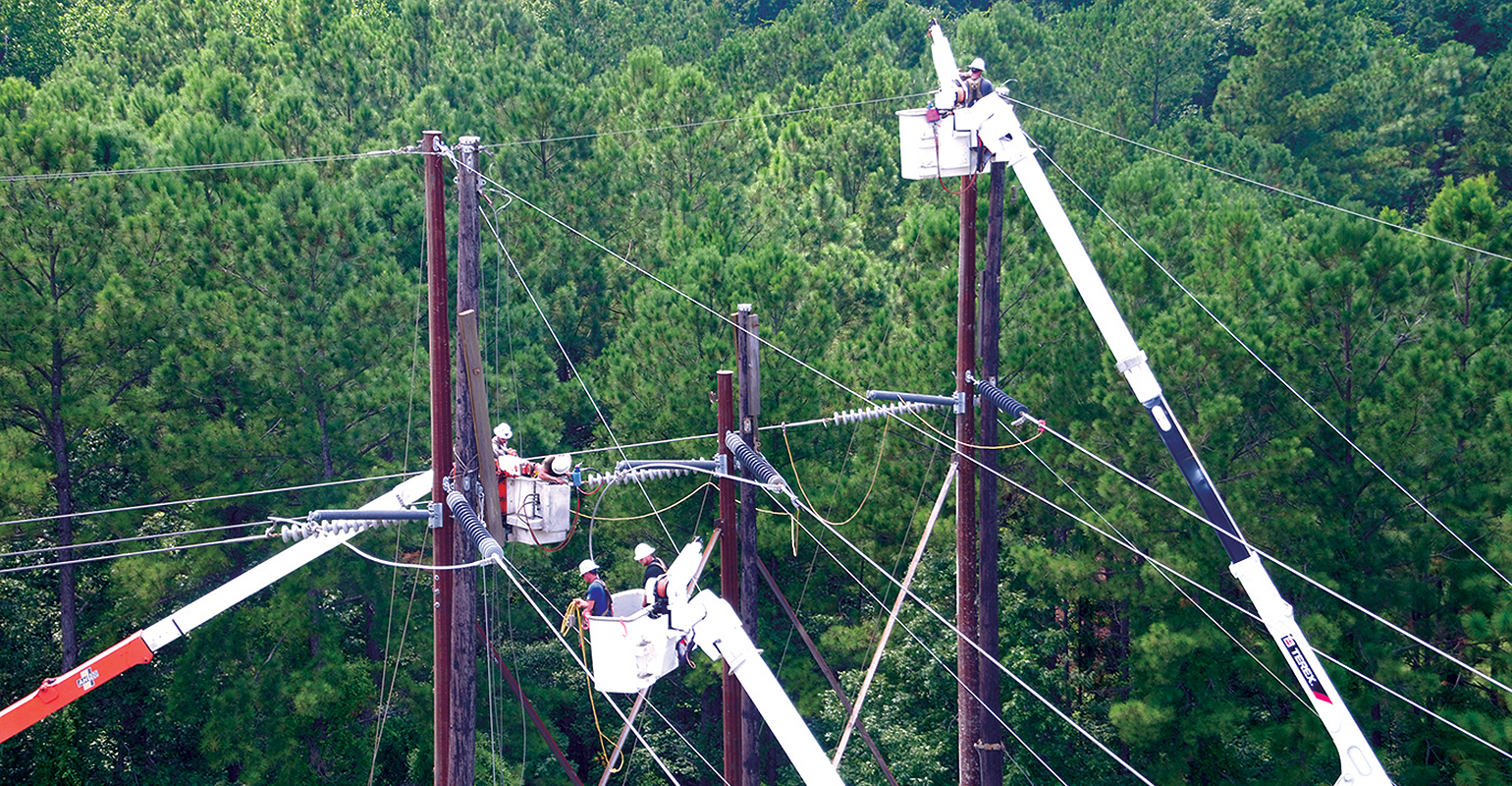 Linemen stand on cranes to work on power lines