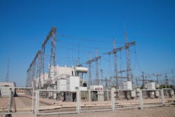 A fenced high-voltage station against the blue sky A fenced high-voltage station against the blue sky