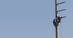 Two men working on an urban transmission line Two men working on an urban transmission line