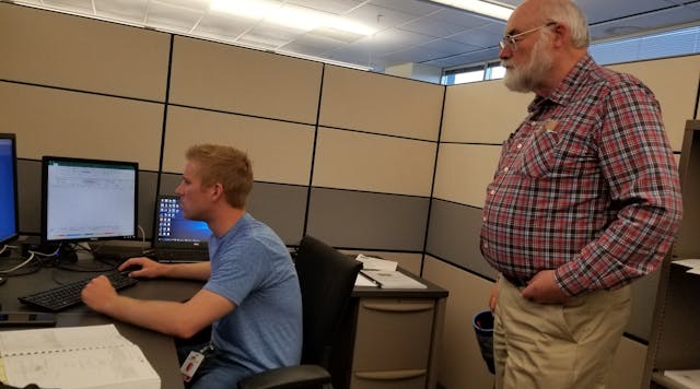 Dean Stange, principal electrical designer at Stanley Consultants, assists distribution designer Cody Schuster on overhead distribution design issues for a project in Colorado. Stange has been mentoring young engineers for four decades.
