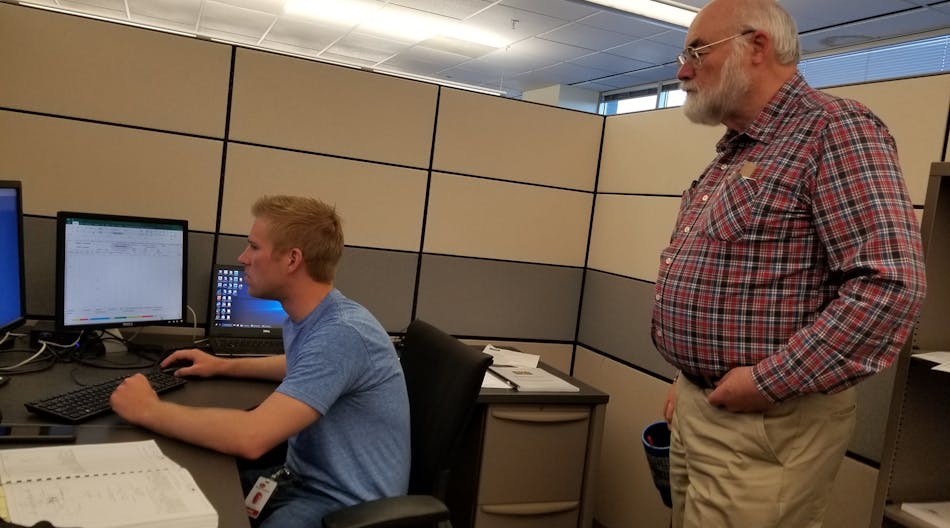 Dean Stange, principal electrical designer at Stanley Consultants, assists distribution designer Cody Schuster on overhead distribution design issues for a project in Colorado. Stange has been mentoring young engineers for four decades.