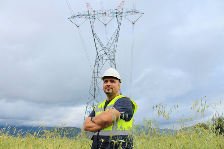 worker in front of transmission tower