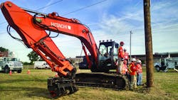 A crane with workers standing around it in an outdoor site A crane with workers standing around it in an outdoor site