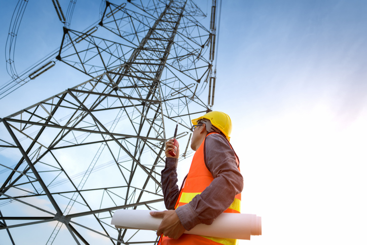 A worker assessing an electric transmission tower