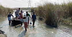 Overhead construction workers travel to tower position by boat for river crossing structure work Overhead construction workers travel to tower position by boat for river crossing structure work