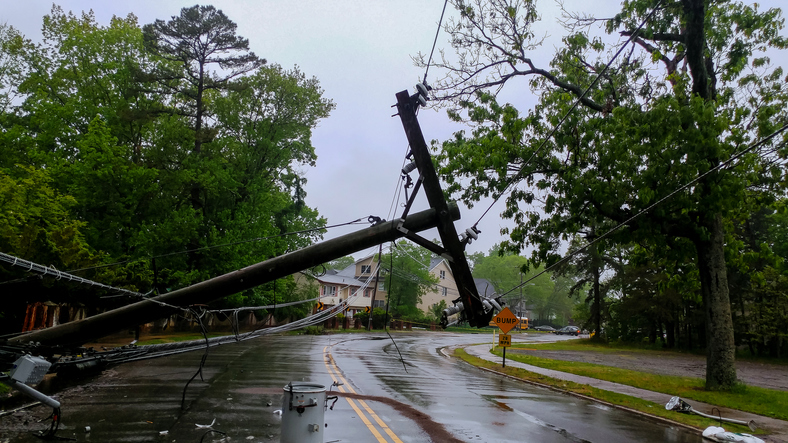 Damaged power lines hanging over a road after a storm