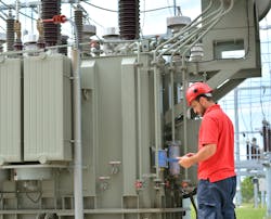 A worker studies looks at some documents near a transformer A worker studies looks at some documents near a transformer
