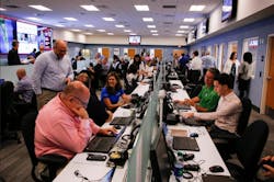 A room full of people working on computers and laptops A room full of people working on computers and laptops