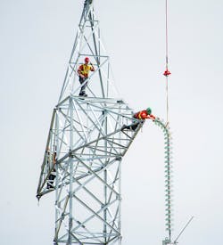 The insulators for one of the poles on a Bipole III HVDC structure are delivered by helicopter during construction.