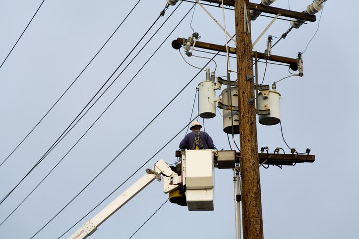 A worker repairing an overhead line on an electric pole
