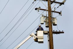 A worker repairing an overhead line on an electric pole A worker repairing an overhead line on an electric pole