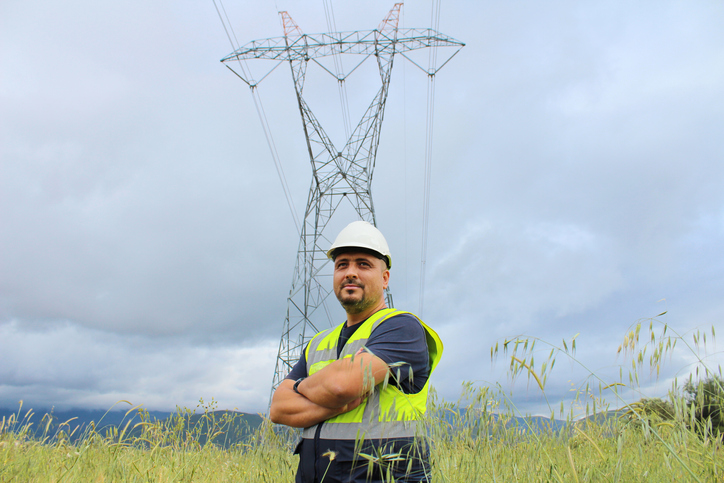 An engineer in front of an electric transmission tower and overhead lines