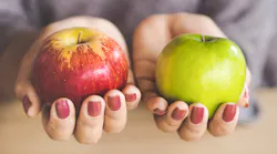 A pair of hands holding a green and a red apple
