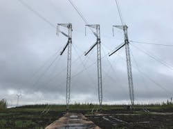 Crews installing OPGW at a three mast guyed deadend structure in a peat bog Crews installing OPGW at a three mast guyed deadend structure in a peat bog